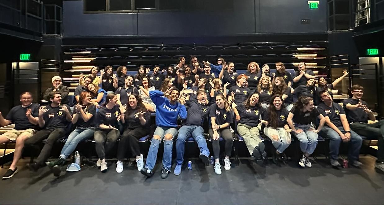 A sea of blue shirts and big smiles as the whole crew strikes goofy poses together.