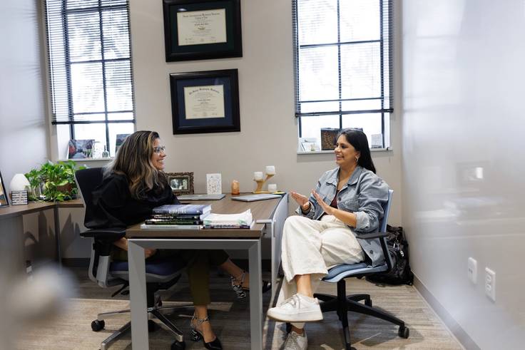 A professor and a student talk during an advising session.