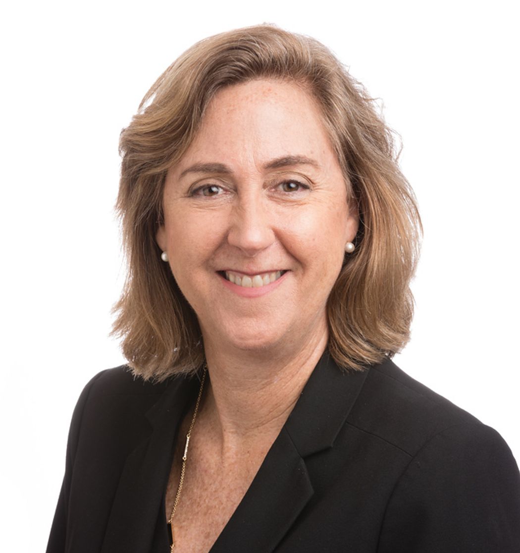 Headshot of a woman with brown hair in a black suit jacket