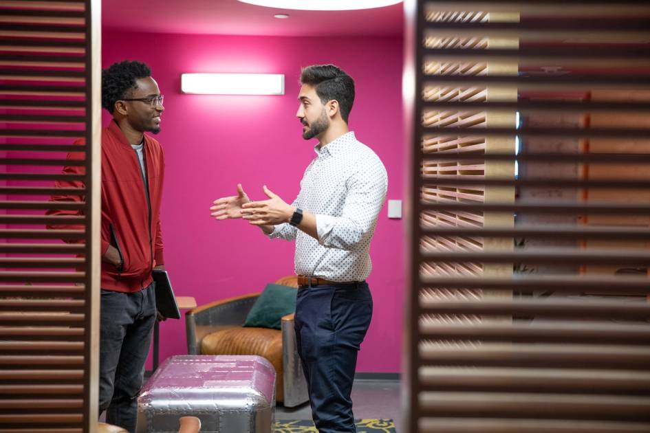 Two colleagues having a casual conversation in a modern, colorful office