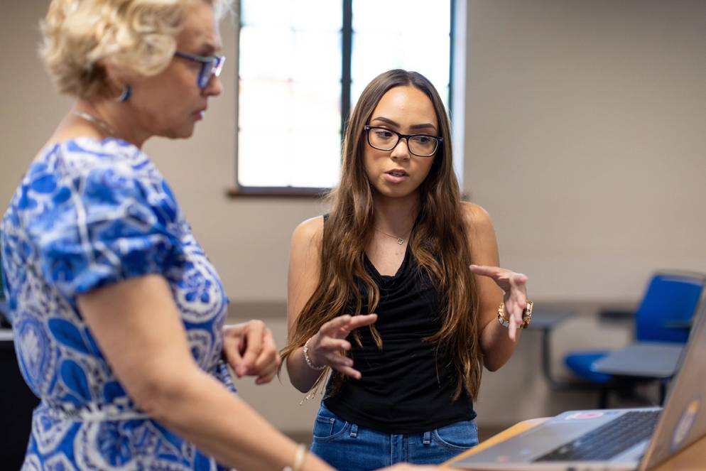 A student and professor work together over a laptop in a Rollins classroom.