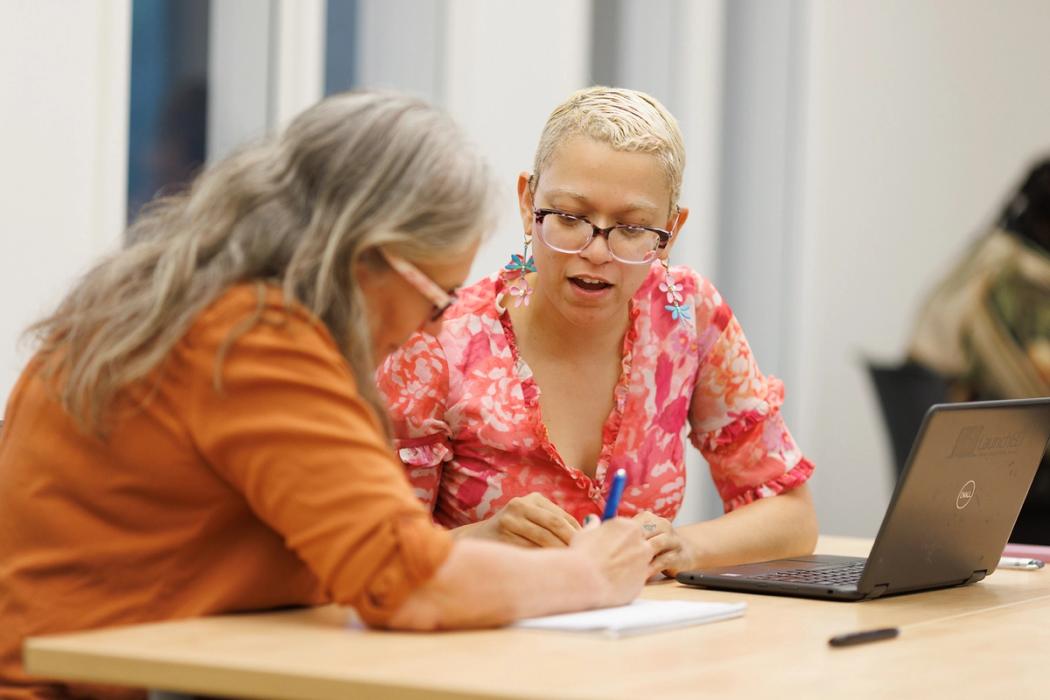 An adult college student smiles as she works with classmates on a project.