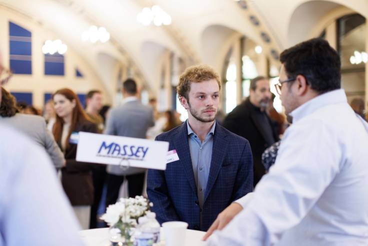 Two professionally-dressed men standing at a table during a career fair. 