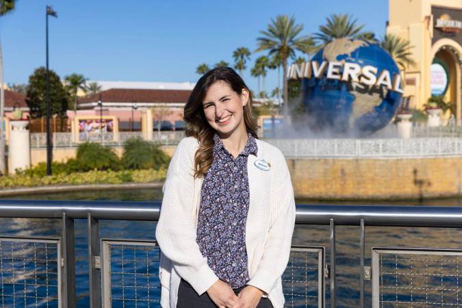 A Rollins graduate poses in front of a globe at Universal Orlando Resort.
