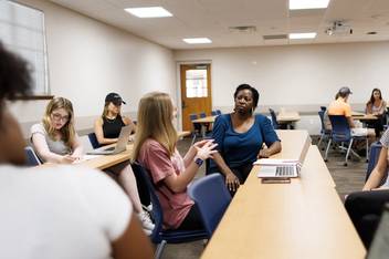 A professor discusses a health-care issue with her students.