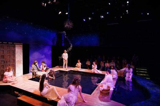 From a production of Metamorphoses, actors gathered around a pool of water.