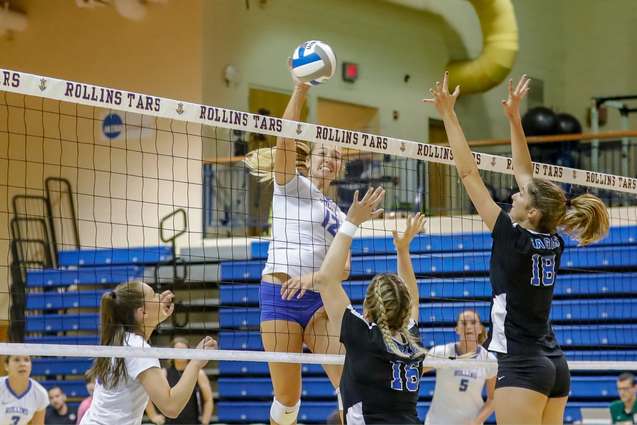 A middle hitter on the volleyball team hitting at the net.