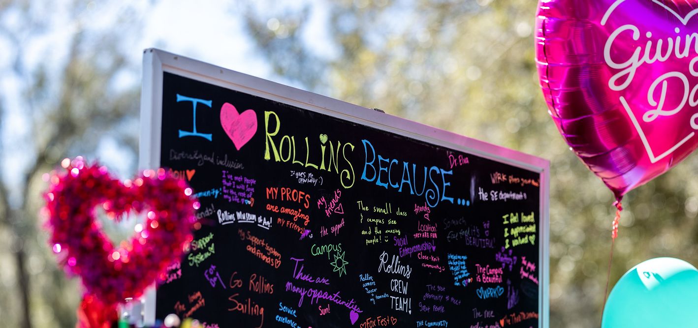 Students writing on a chalkboard outside with the title I Love Rollins Because