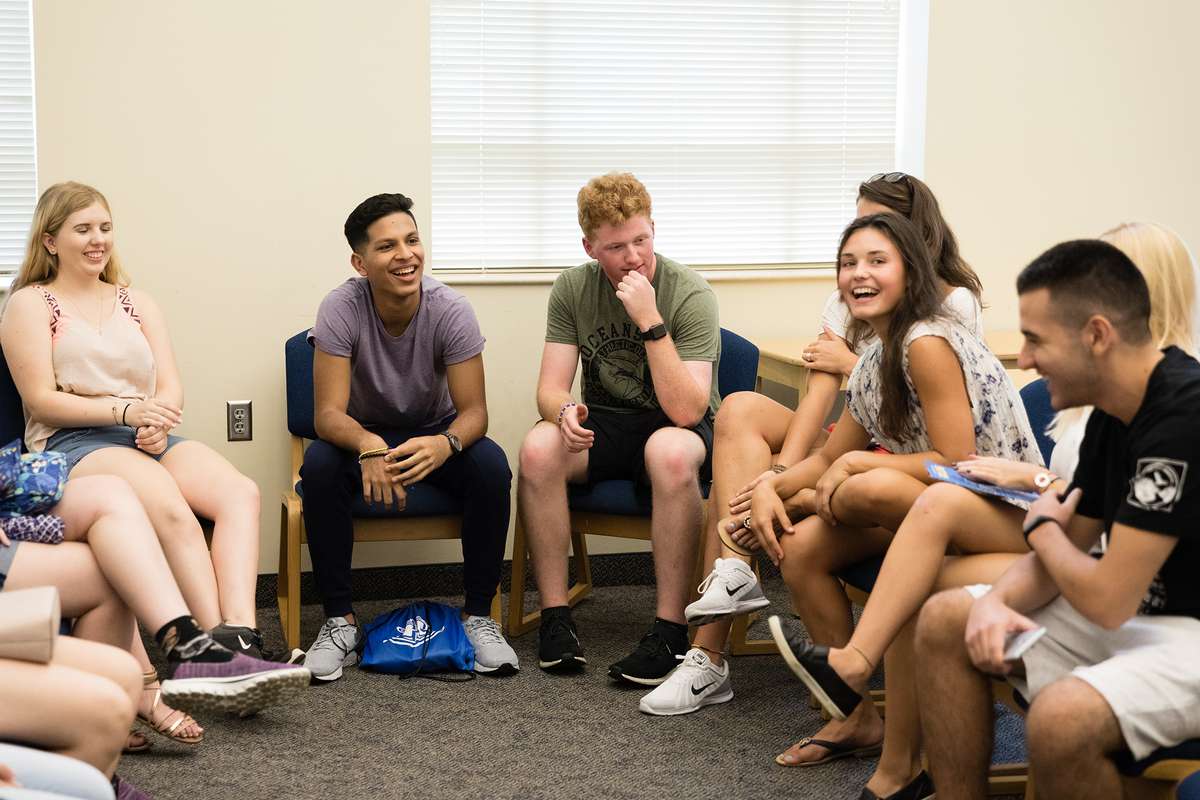 Students sit in a circle and laugh together during a first-year college class.