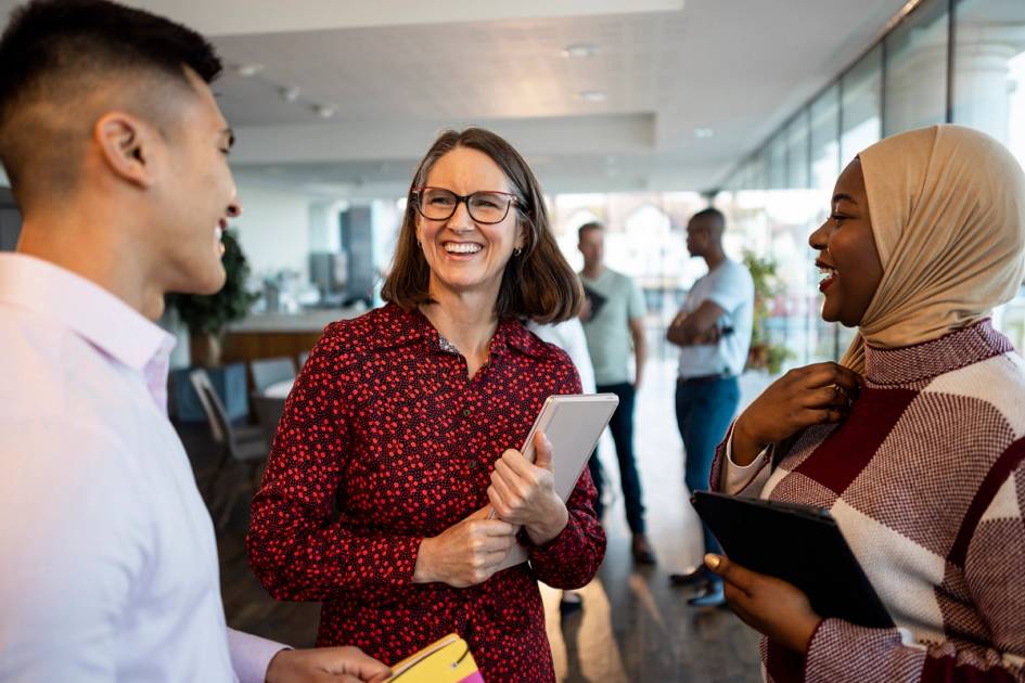 Colleagues smiling and chatting informally while networking in a modern office.