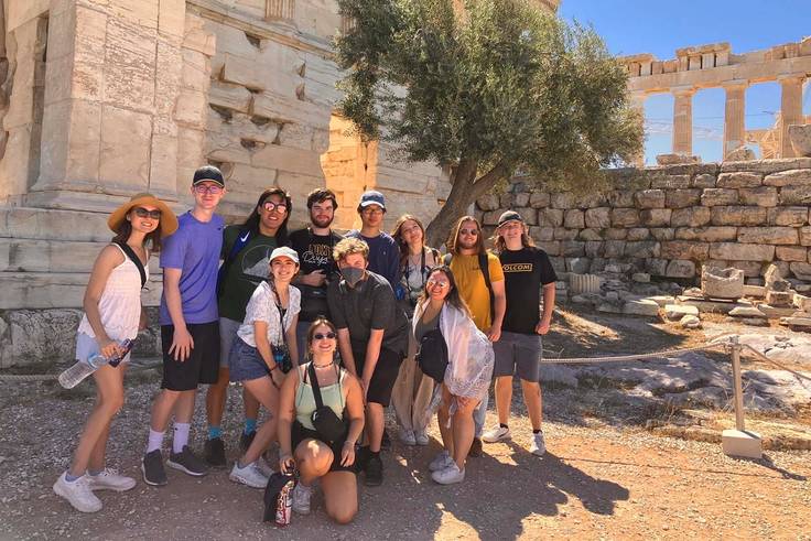 Students pose in front of ancient ruins in Greece.