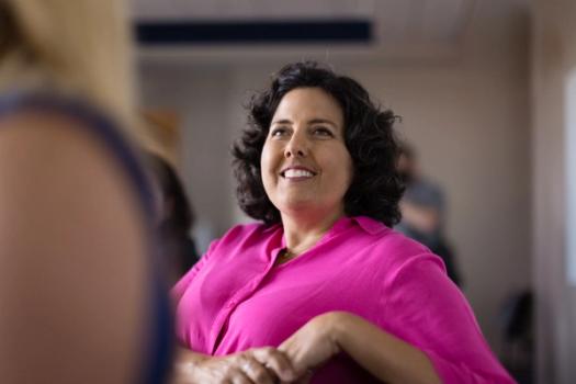 An adult college student smiles during a class session.