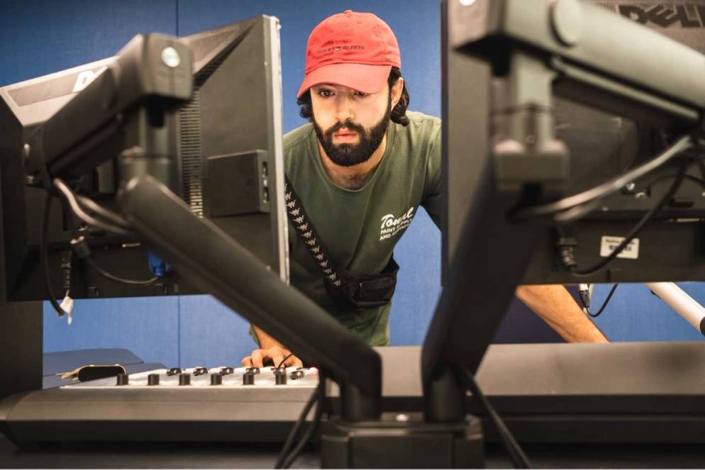 A member of student media hovers over a soundboard.