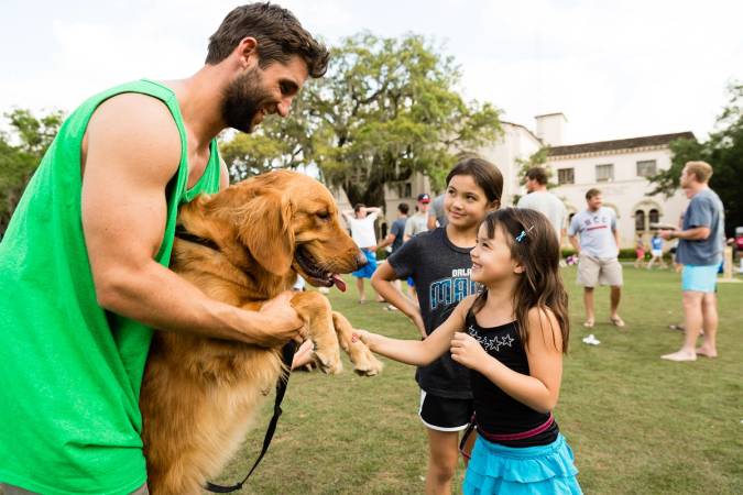 A young girls shakes hands with a golden retriever on Mills Lawn.