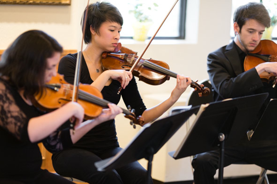 String quartet musicians performing with violins in an indoor rehearsal space