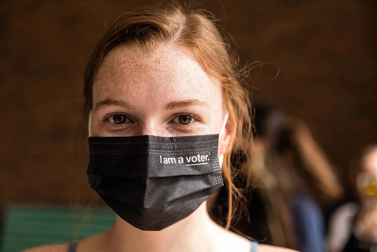 A portrait of a student wearing an I am a voter face mask.
