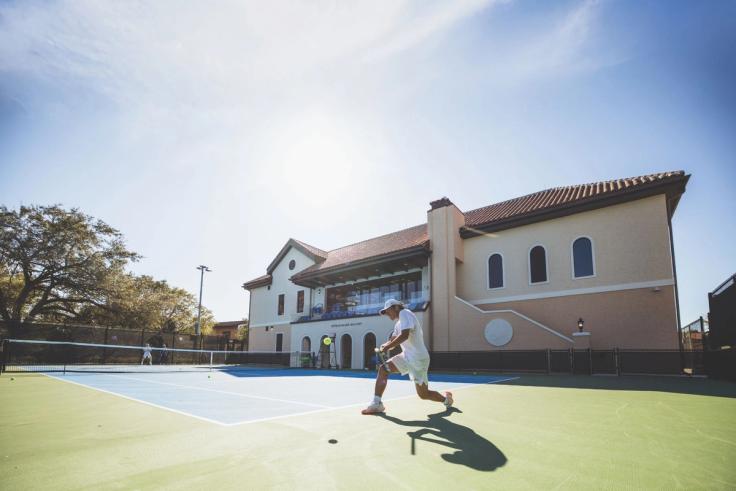 Rollins tennis student-athlete hitting a forehand on outdoor court beside the Tennis & Golf Center.