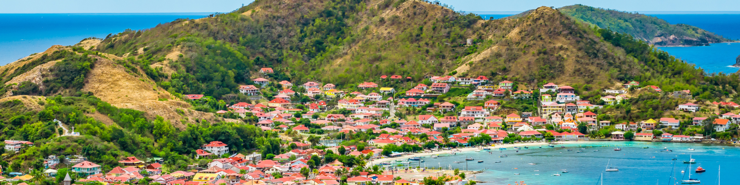 Image of mountains and town in Guadeloupe with boats on the water.