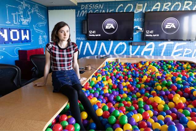 A recent college alumn with her legs in a ball pit at EA Sports.