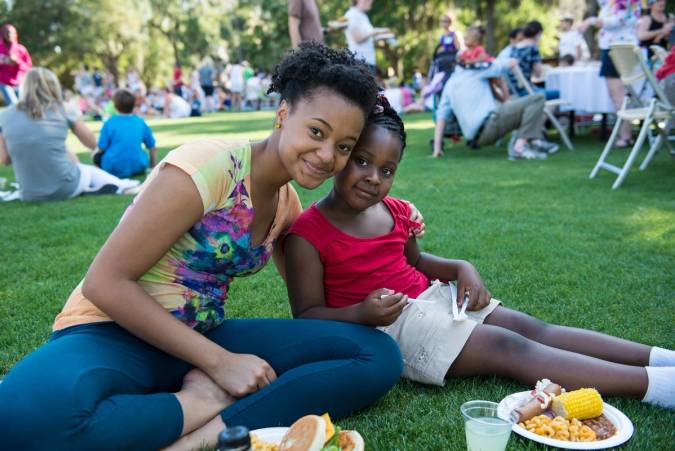 A student and young girl pose during a picnic on Mills Lawn.