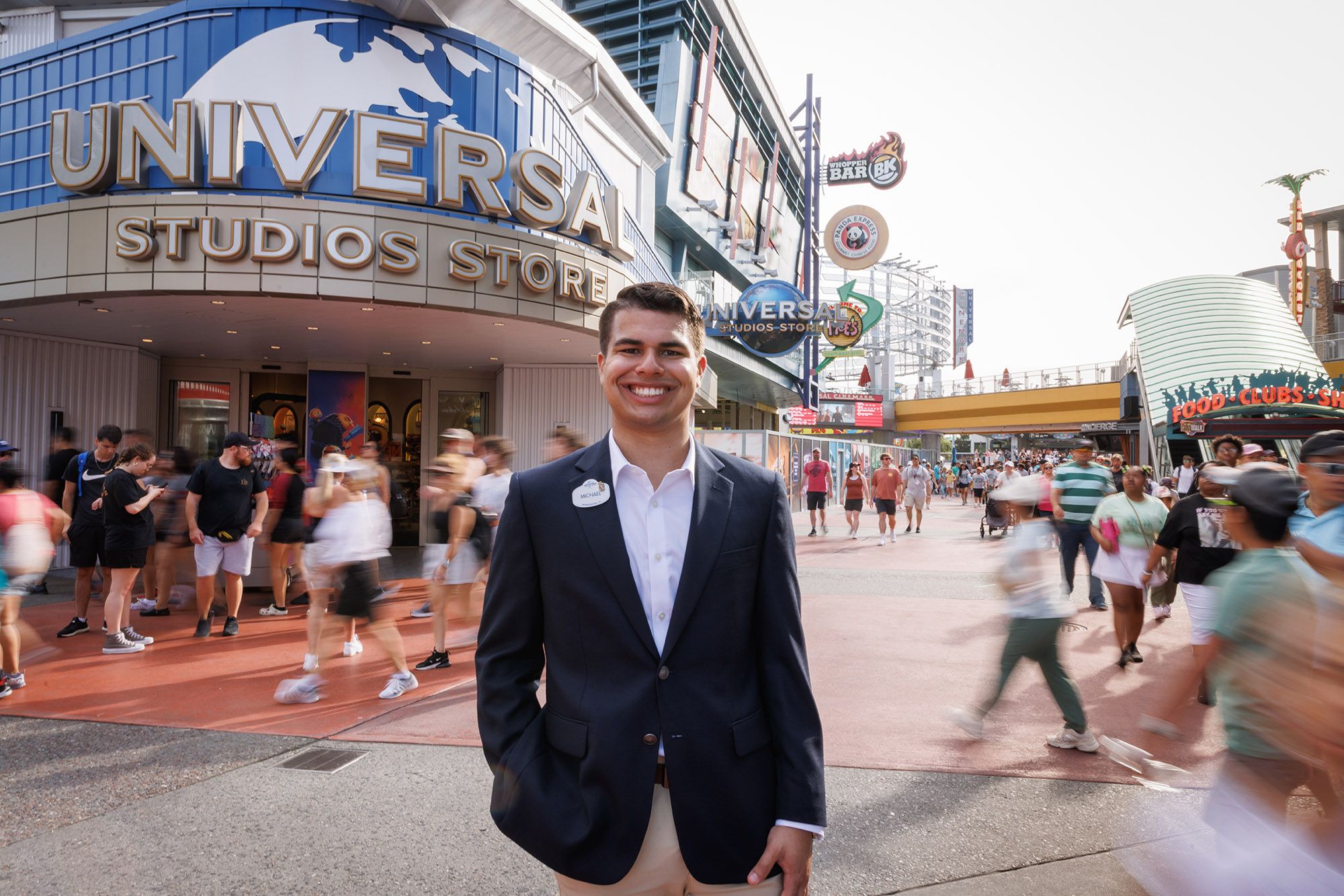 Smiling staff member welcomes visitors outside the Universal Studios Store.