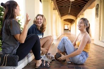 A group of Rollins College students sitting outdoors and talking. 