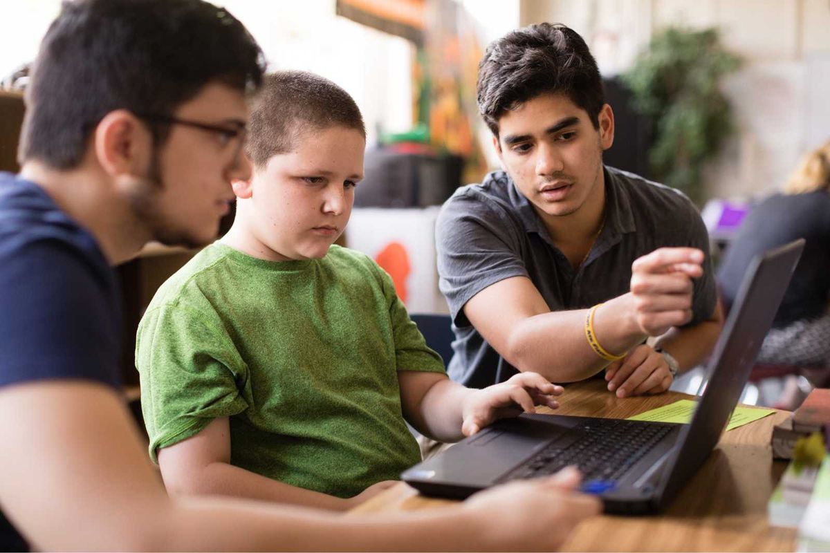 Students gathered around a laptop.