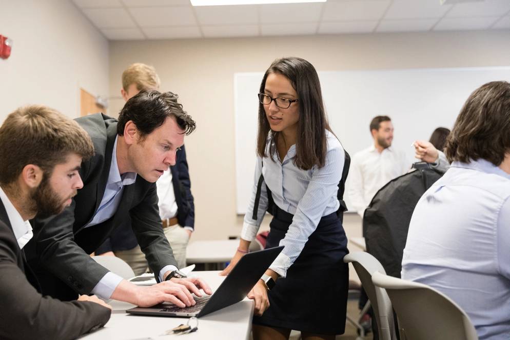 International business students meet with professor.