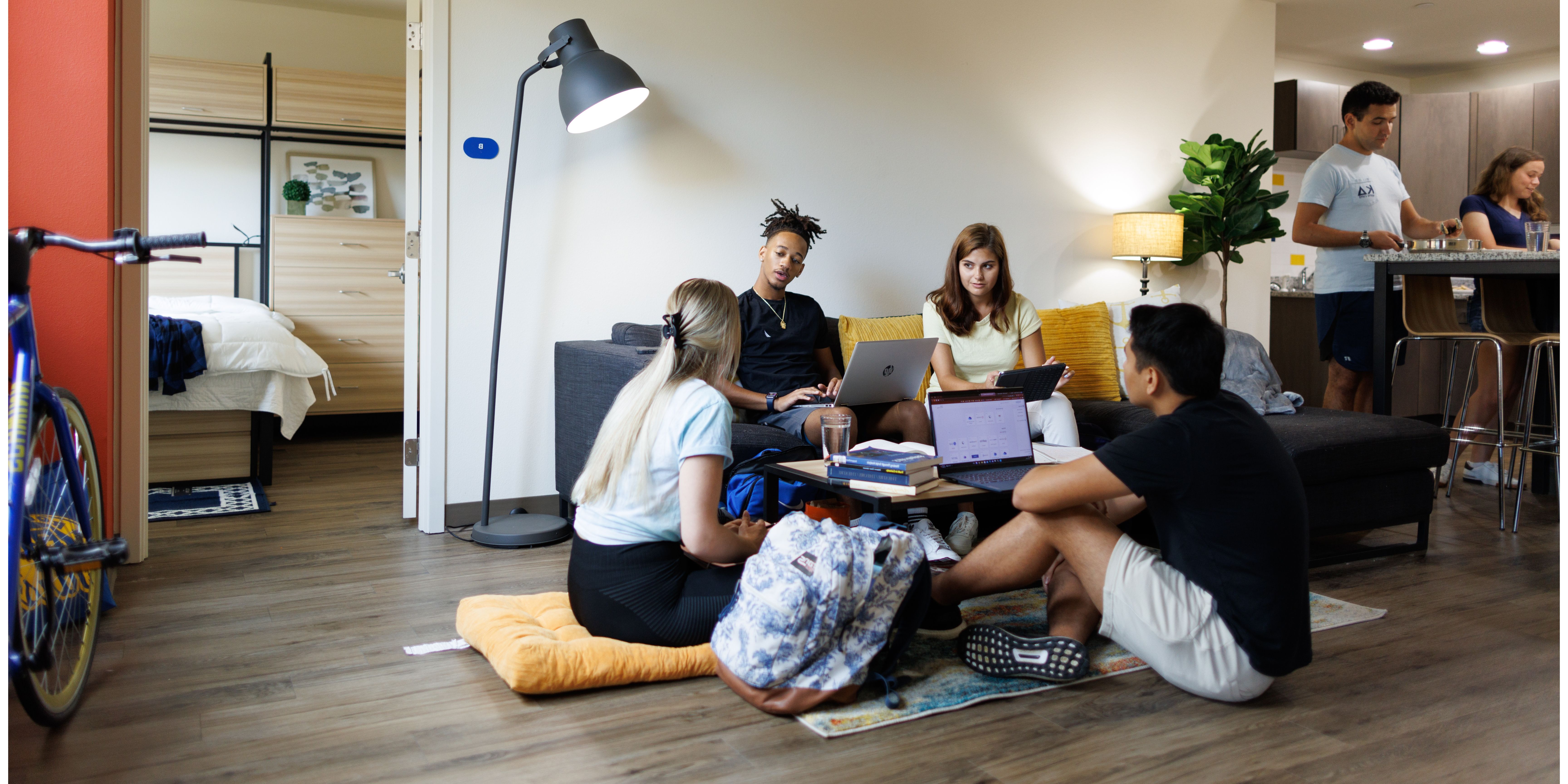 A group of students laughs and talks in a Rollins College dorm room.