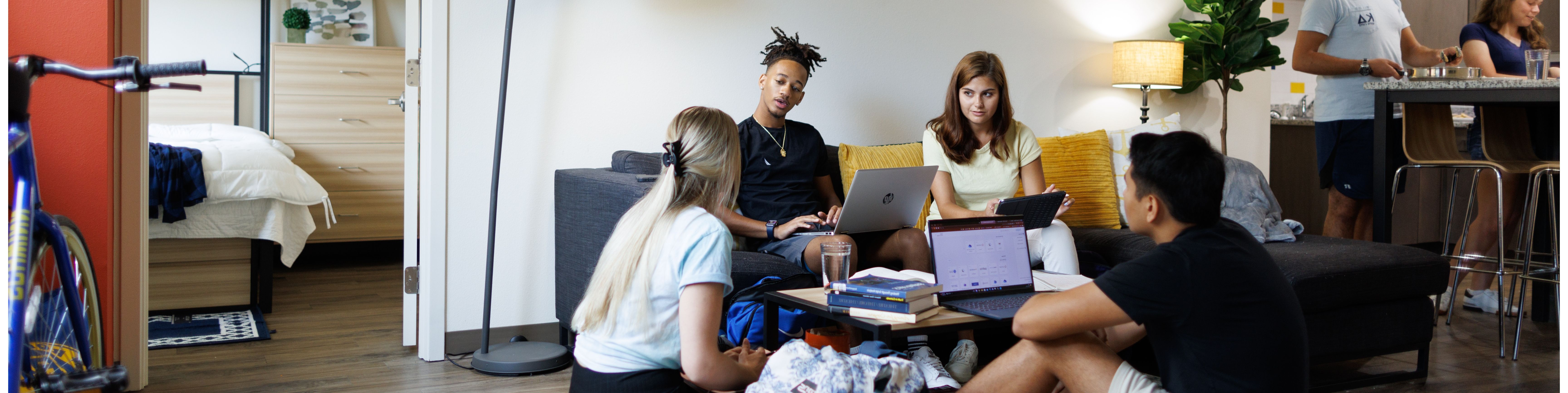 A group of students laughs and talks in a Rollins College dorm room.