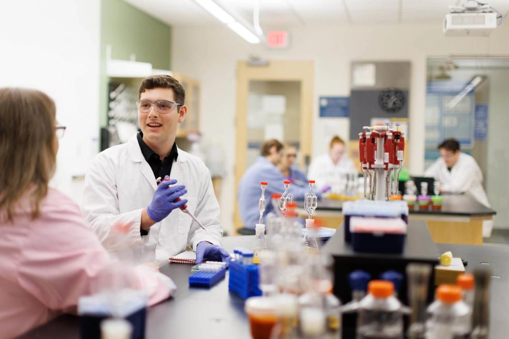 A student works with a professor in a chemistry lab.