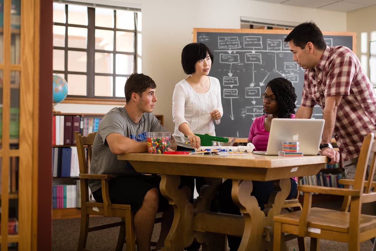 A classroom with a teacher and three college-age students