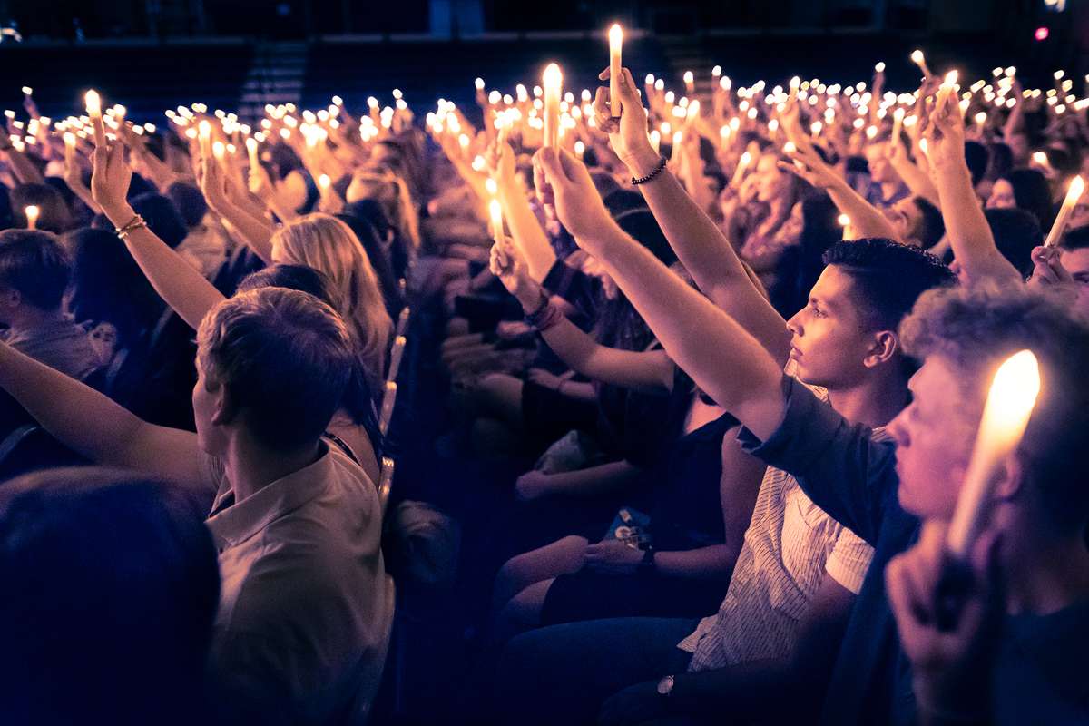 College students raise candles in a dimly lit chapel.