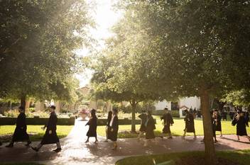 Students walk past the rose garden on their way to commencement.