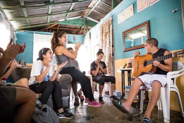 Students join in the celebration as a local Dominican Republic boy plays the guitar. boy plays the guitar.