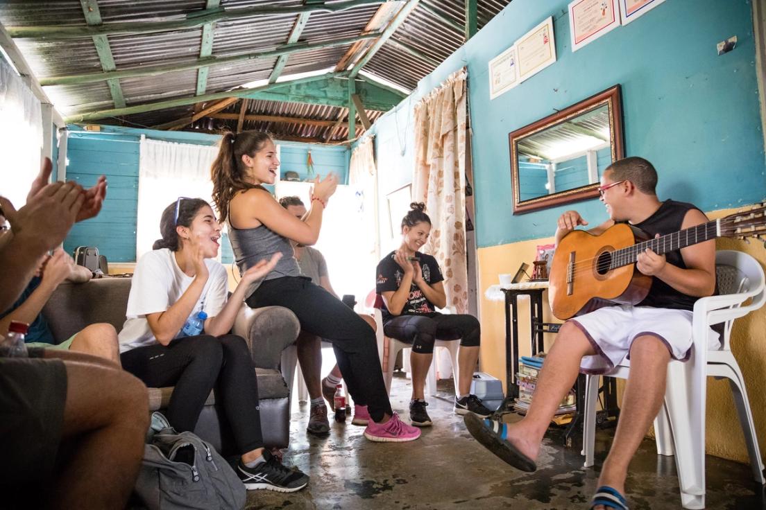 Students join in the celebration as a local Dominican Republic boy plays the guitar. boy plays the guitar.