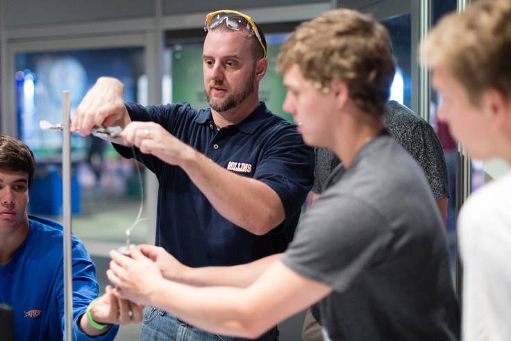 Physics professor Chris Fuse assists his students with a lab focused on weights and measures.
