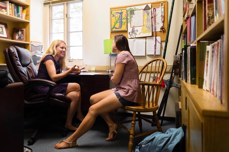 A professor advises a student one on one.