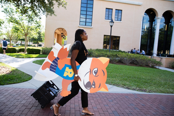 Happiness Omochere ’20 carrying a cardboard-cutout fox for an on-campus event promoting #RollinsLife.