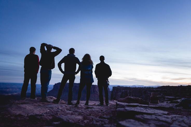 Five students look out over a national park from the top of a cliff.