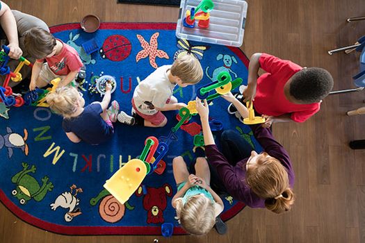 Children playing together on an alphabet rug.