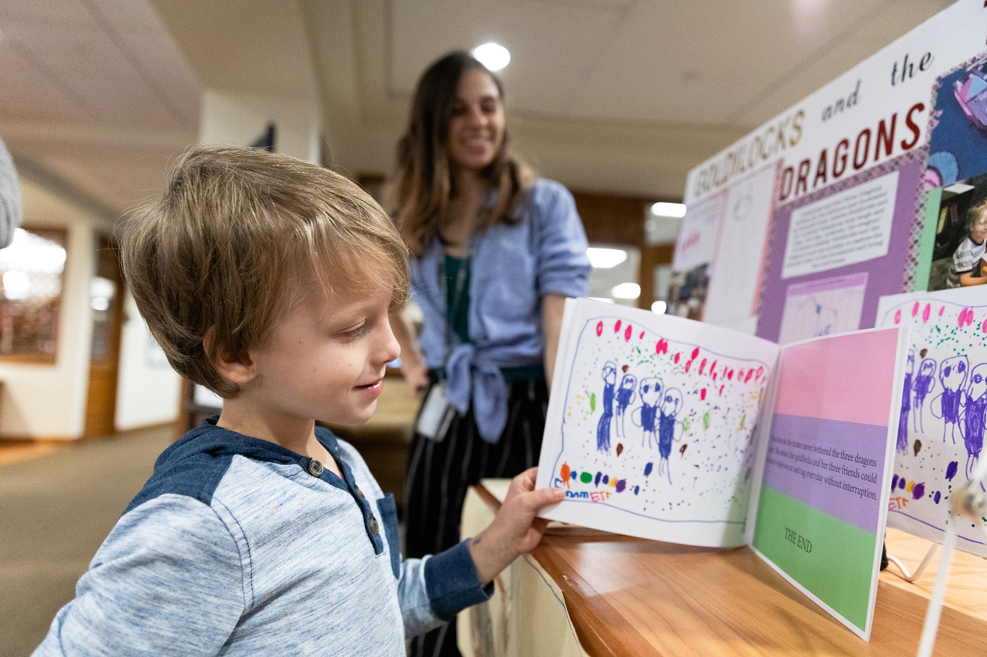 A young boy admires the book he wrote with help from a Rollins student.