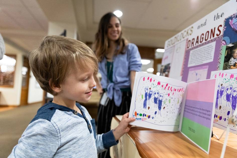 Child and student looking at a book