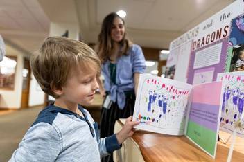 A child from Rollins’ Child Development Center reads the book helped write with a Rollins student.
