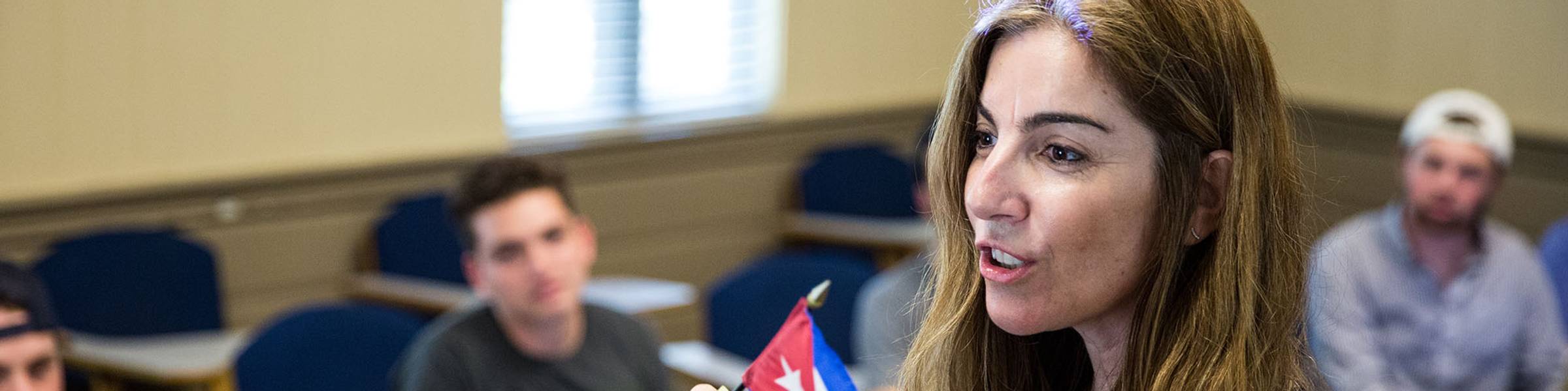 Latin American & Caribbean studies professor speaks to class while holding many country's flags.