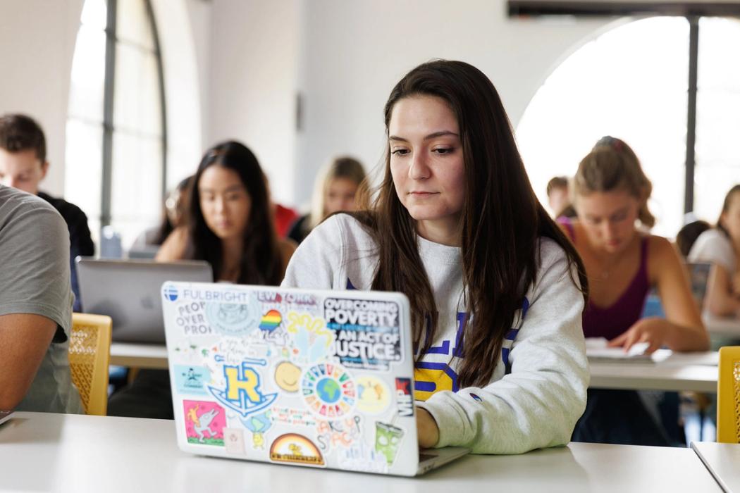 A Rollins student works on a laptop in the classroom.