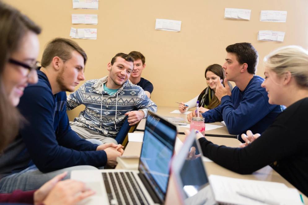 Students at their desks smiling and discussing the topic of the day.