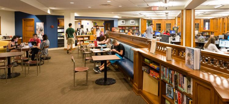 A counter and seating area in a library, chairs and tables and low book shelves