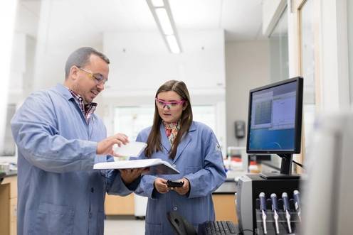 A student and professor collaborate in a chemistry lab.