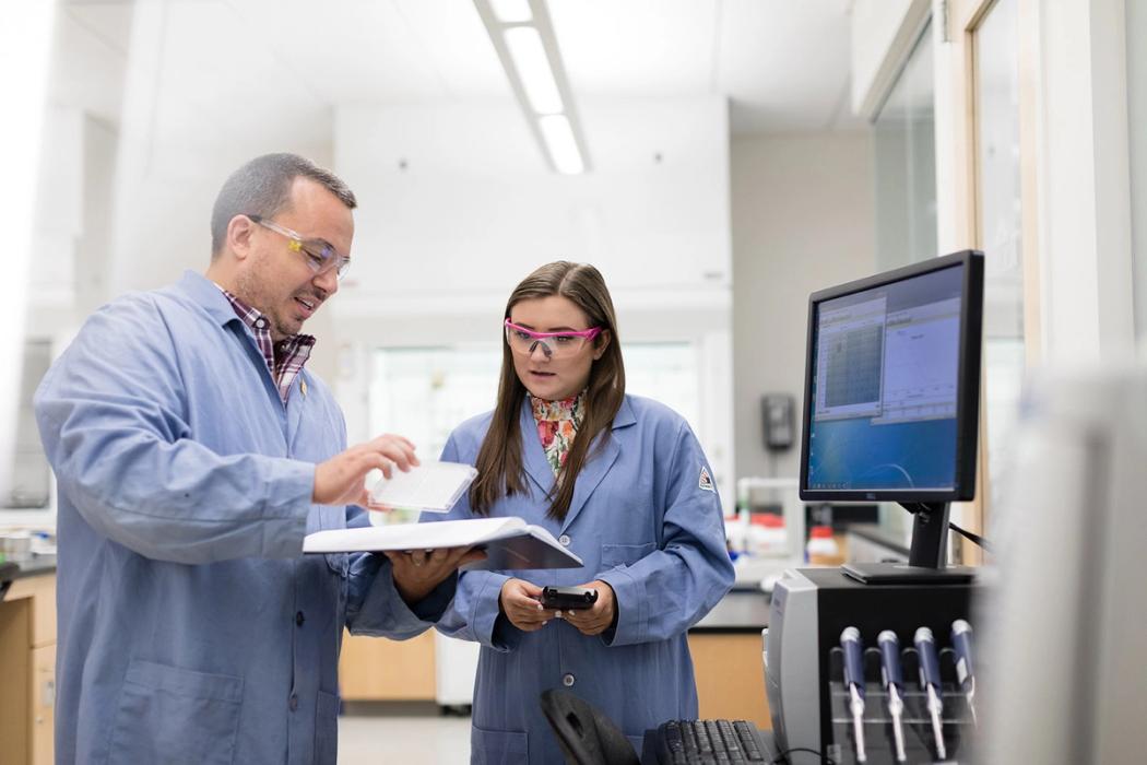 A student and professor collaborate in a chemistry lab.